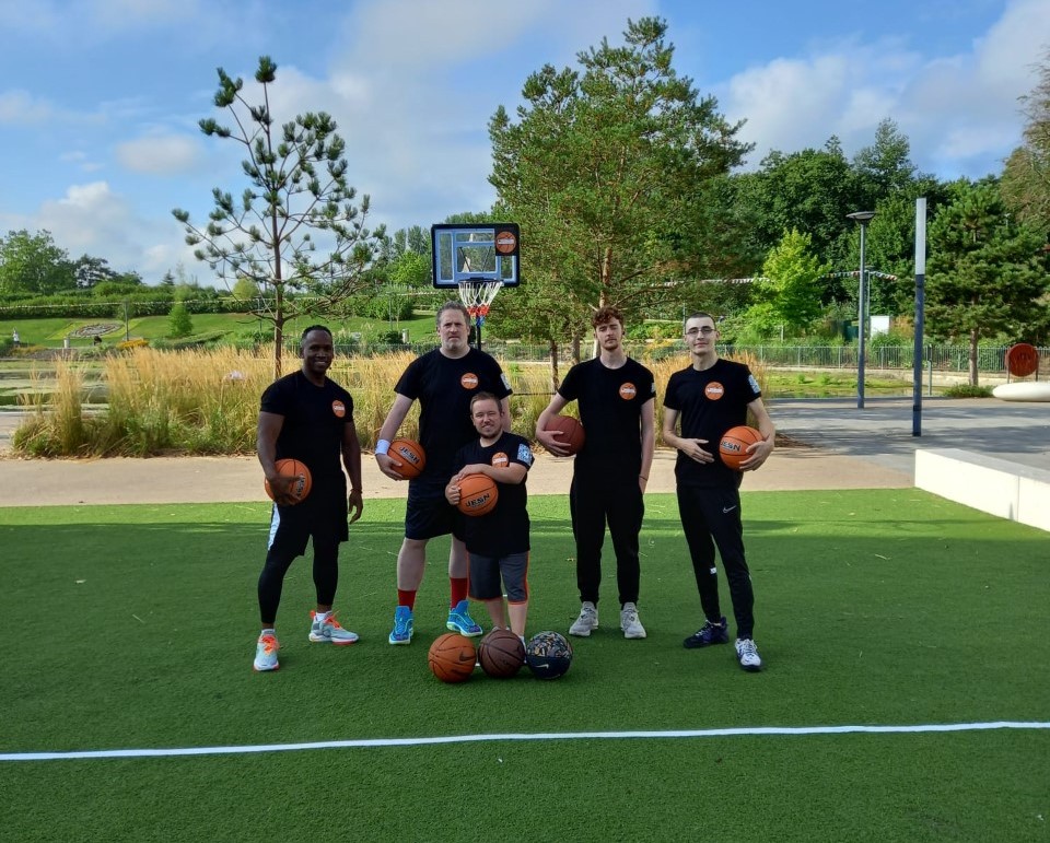 Players holding basketballs on an outdoor court at a community session
