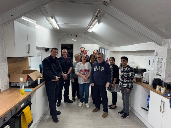 Volunteers and partner organisation staff standing together in the Community Hub kitchen