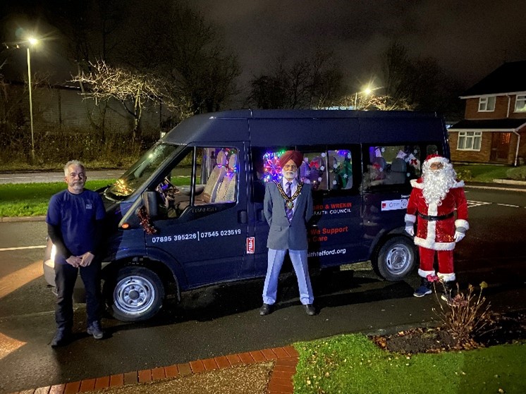 The Interfaith Mobile Santa Grotto van lit up at night with volunteers and Father Christmas