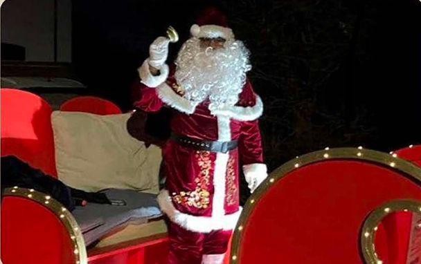 Interfaith Father Christmas ringing a bell on the Mobile Santa Grotto sleigh in December 2023