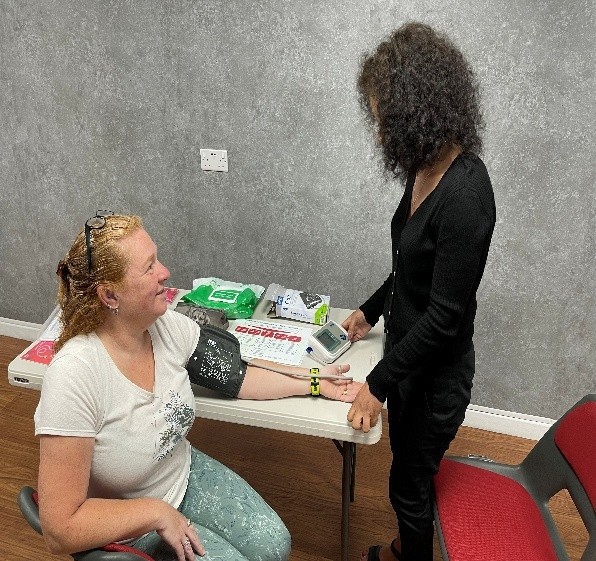 A health worker taking a resident's blood pressure at a health session held in the Community Hub